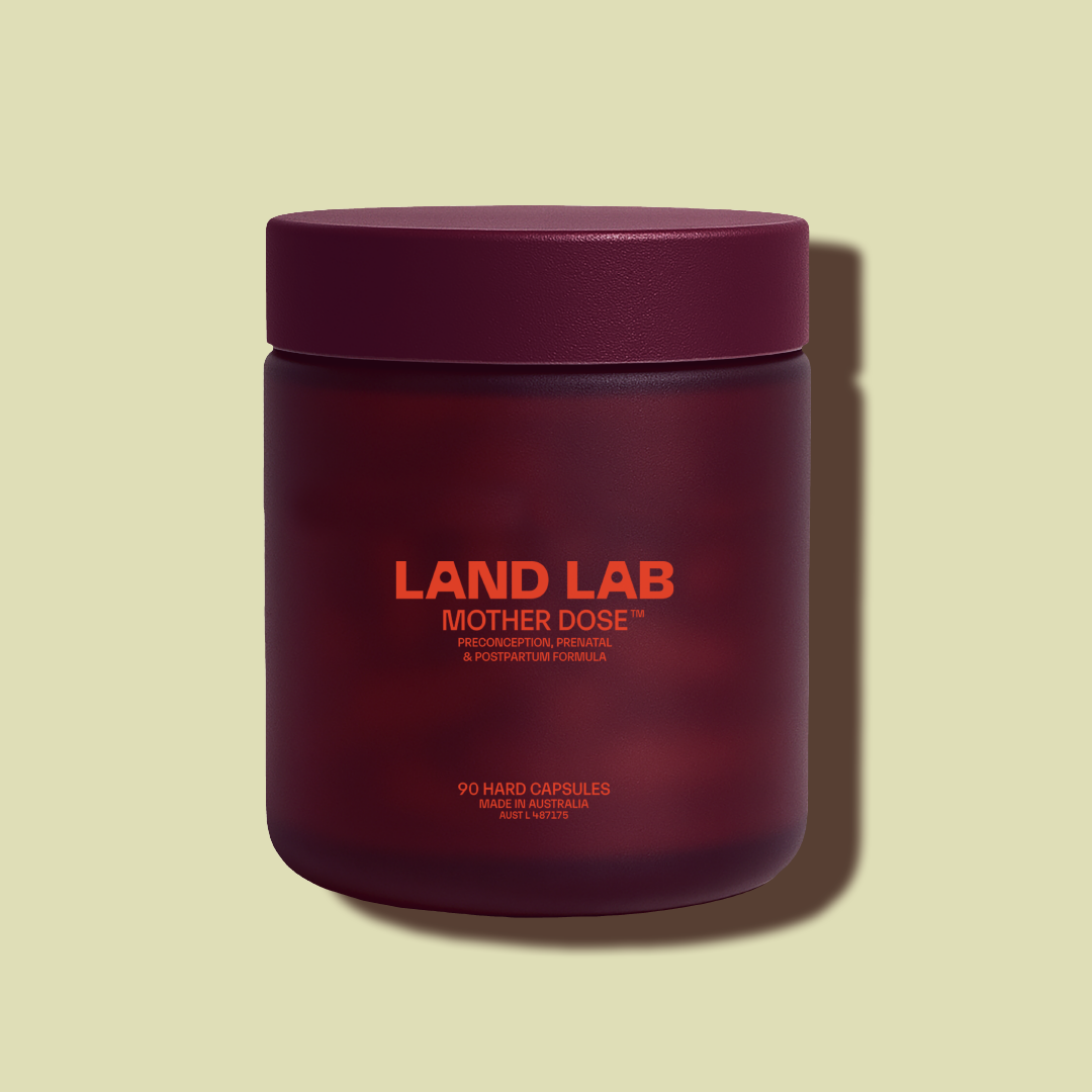Purple glass jar of Land Lab Mother Dose prenatal multivitamin on a pale green background, showing 90-capsule packaging.